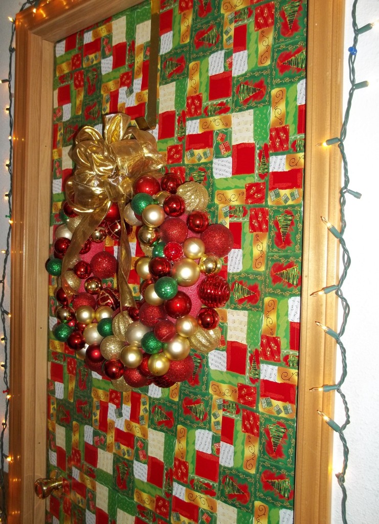 This door has music in the wrapping paper, a string of lights around the frame, and a beautiful wreath made with Christmas ornaments.